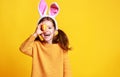 Funny happy child girl with easter eggs and bunny ears on yellow Royalty Free Stock Photo