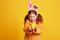 Funny happy child girl with easter eggs and bunny ears on yellow Royalty Free Stock Photo