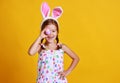 Funny happy child girl with easter eggs and bunny ears on yellow Royalty Free Stock Photo