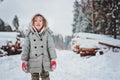 Funny happy child girl portrait on the walk in winter snowy forest with tree felling on background Royalty Free Stock Photo