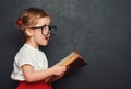 Funny happy girl schoolgirl with book from blackboard Royalty Free Stock Photo