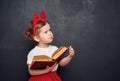 Funny happy girl schoolgirl with book from blackboard Royalty Free Stock Photo