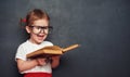 Funny happy girl schoolgirl with book from blackboard