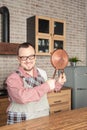 Funny happy smiling man wearing pinafore holding kitchen utensils