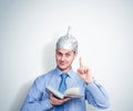 Funny happy man in an aluminum foil hat holds a book and preaches. Concept art phobias