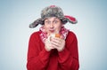 Funny happy man in a red sweater, scarf and winter hat holds a mug of hot drink in his hands