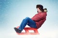 Funny happy man in winter clothes fly on a sled in the snow Royalty Free Stock Photo