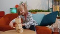 Funny happy one teenage kid girl play wooden tower blocks bricks game at home in modern living room