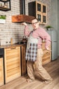 Funny happy smiling man wearing pinafore dancing on the kitchen