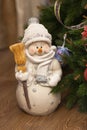 Funny happy snowman with broom by the christmas tree in evening time. Homemade festive cozy atmosphere. Front view. Vertical