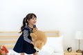 Funny happy toddler girl jumping and playing with her toy teddy bear in bed. Kids play at home. Royalty Free Stock Photo
