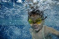 Funny happy toddler girl swimming underwater in a pool with lots of air bubbles Royalty Free Stock Photo