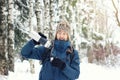 Funny hiker in warm clothes pours tea in mug from thermos in winter forest. Tea ended and the man in comic horror. Season concept