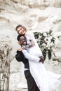 Funny hippy couple African man and Caucasian woman dressed in boho style are staying before the wedding arch in canyon