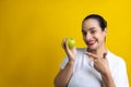 Funny Hispanic woman pointing to a green apple on a yellow background