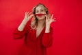 Funny, humorous, confident blonde woman in red dress hold red chili pepper in hands under nose like mustache. Hot news Royalty Free Stock Photo