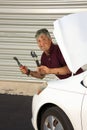 Funny humorous mechanic covered in grease with confused look on his face