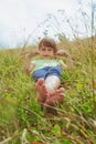 Funny image of cte little child girl grass against mountains under sunlight on sunny day. Happiness, childhood and carefree