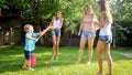 Funny photo of happy family with children playing and splashing water with water guns and garden hose at hot sunny day Royalty Free Stock Photo