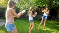 Funny photo of happy family with children playing and splashing water with water guns and garden hose at hot sunny day Royalty Free Stock Photo