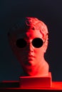 Funny image of a red-lit marble head of young man in sunglasses over black