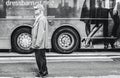 Funny image of a senior man seen on a city road next to a travel coach which is advertising clothing.