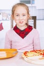 Funny imahe of little cute child girl eating a piece of pizza. Happy childhood, food, rest and joy concept