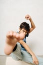 Funny indian boy sitting on a wooden box, touching camera lenz with his foot Royalty Free Stock Photo