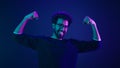 Funny Indian man slim guy fooling around show hands muscle biceps sport strong power bodybuilder ultraviolet neon studio