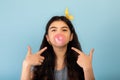 Funny Indian teen girl blowing bubble from sugar free chewing gum, pointing at it over blue studio background Royalty Free Stock Photo