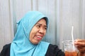 Funny Indonesian Muslim Woman Wearing Hijab and Laughing While Holding Her Iced Tea Infront of Silver Background