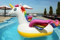 Funny inflatable unicorn ring floating in swimming pool on sunny day