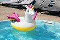Funny inflatable unicorn ring floating in swimming pool on sunny day
