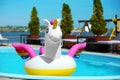 Funny inflatable unicorn ring floating in swimming pool on sunny day