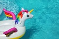 Funny inflatable unicorn ring floating in swimming pool on sunny day