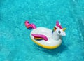 Funny inflatable unicorn ring floating in swimming pool on sunny day