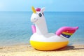 Funny inflatable unicorn ring on sandy beach near sea