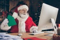 Funny jolly holly grey hair santa claus sit table work computer answer kids x-mas wish list letters hold envelope wear Royalty Free Stock Photo