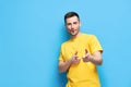 Funny joyful man pointing at you and looking to camera on blue background