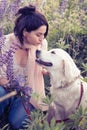 funny joyful portrait of brunette girl with her golden retriever at wonderful blooming Lupines meadow at country side. cloudy