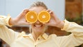 Young woman holding orange slices near her eyes and smiling. Royalty Free Stock Photo