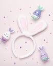 Funny kawaii cute bunny eggs and bunny rabbit ears for kids in pastel colors on pink table top, Easter holiday concept. Easter