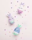 Funny kawaii cute bunny eggs and bunny rabbit ears for kids in pastel colors on pink table top, Easter holiday concept. Easter