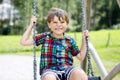 Funny kid boy having fun with chain swing on outdoor playground while being wet splashed with water. child swinging on Royalty Free Stock Photo