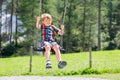 Funny kid boy having fun with chain swing on outdoor playground while being wet splashed with water Royalty Free Stock Photo