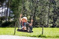 Funny kid boy having fun with chain swing on outdoor playground while being wet splashed with water Royalty Free Stock Photo