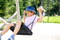Funny kid boy having fun with chain swing on outdoor playground while being wet splashed with water Royalty Free Stock Photo