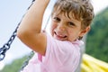 Funny kid boy having fun with chain swing on outdoor playground while being wet splashed with water Royalty Free Stock Photo