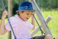 Funny kid boy having fun with chain swing on outdoor playground while being wet splashed with water Royalty Free Stock Photo