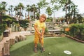 Funny kid boy playing mini golf